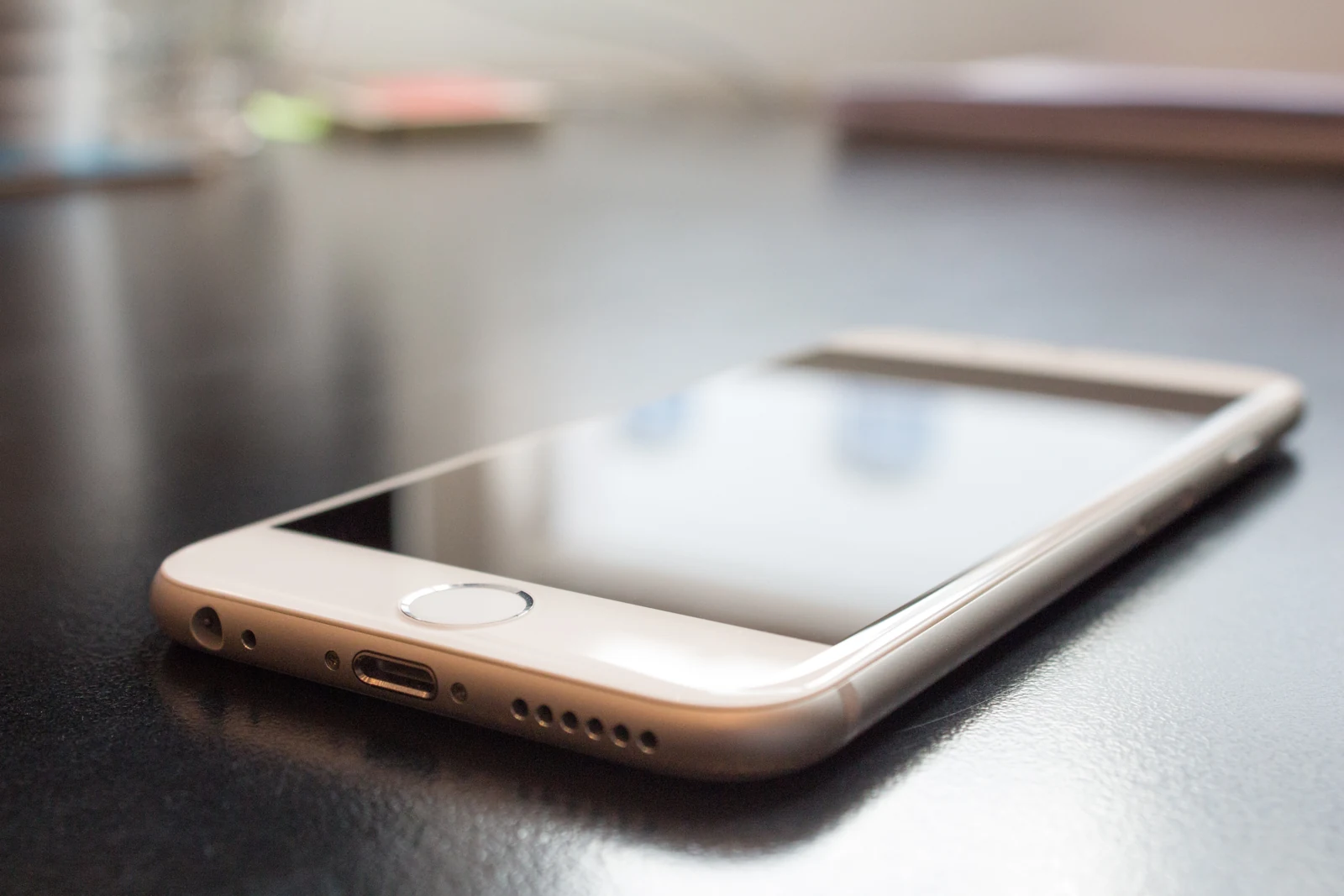 Koyu renkli masa üzerinde ekranı yukarı dönük, beyaz çerçeveli akıllı telefon.